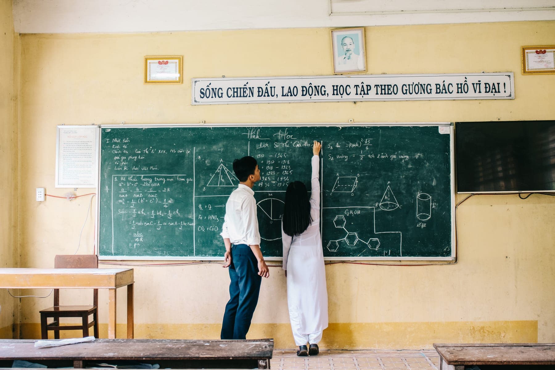 Two students drawing geometry on the classroom blackboard