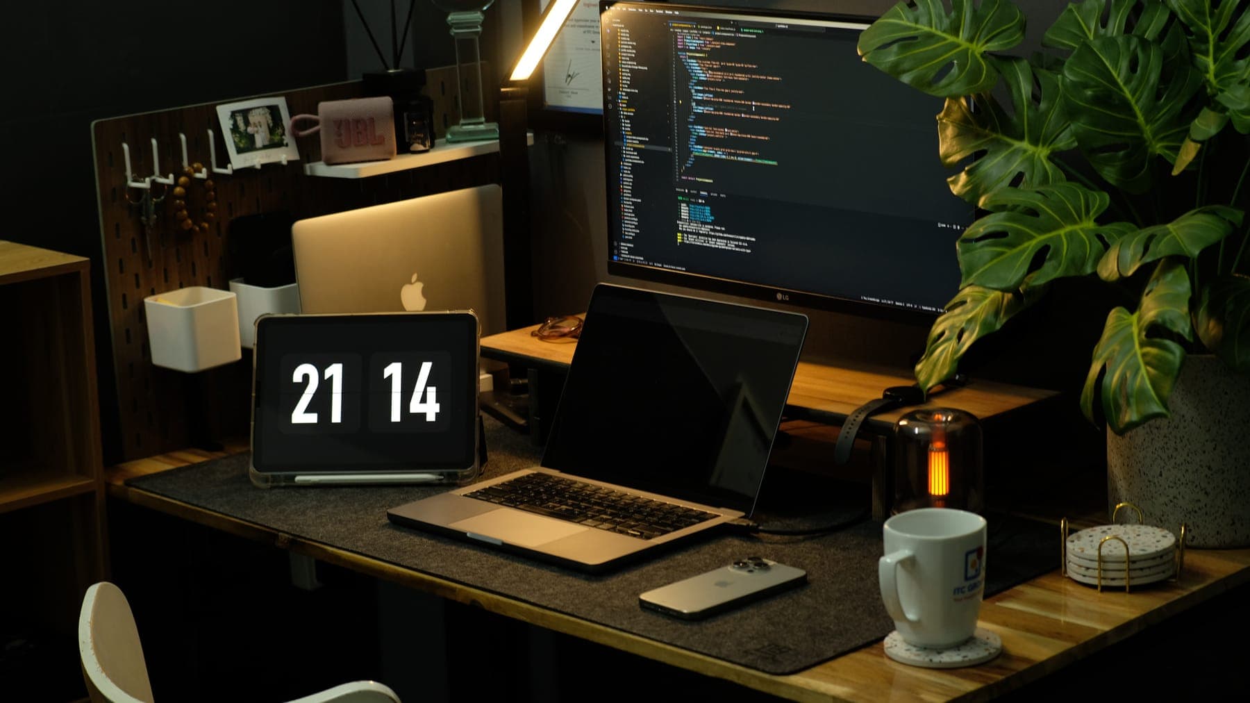 The desk at night with a flip clock at 21:14, laptop and a glowing lantern