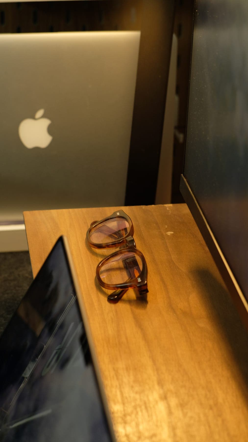A pair of glasses on the edge of a wooden desk