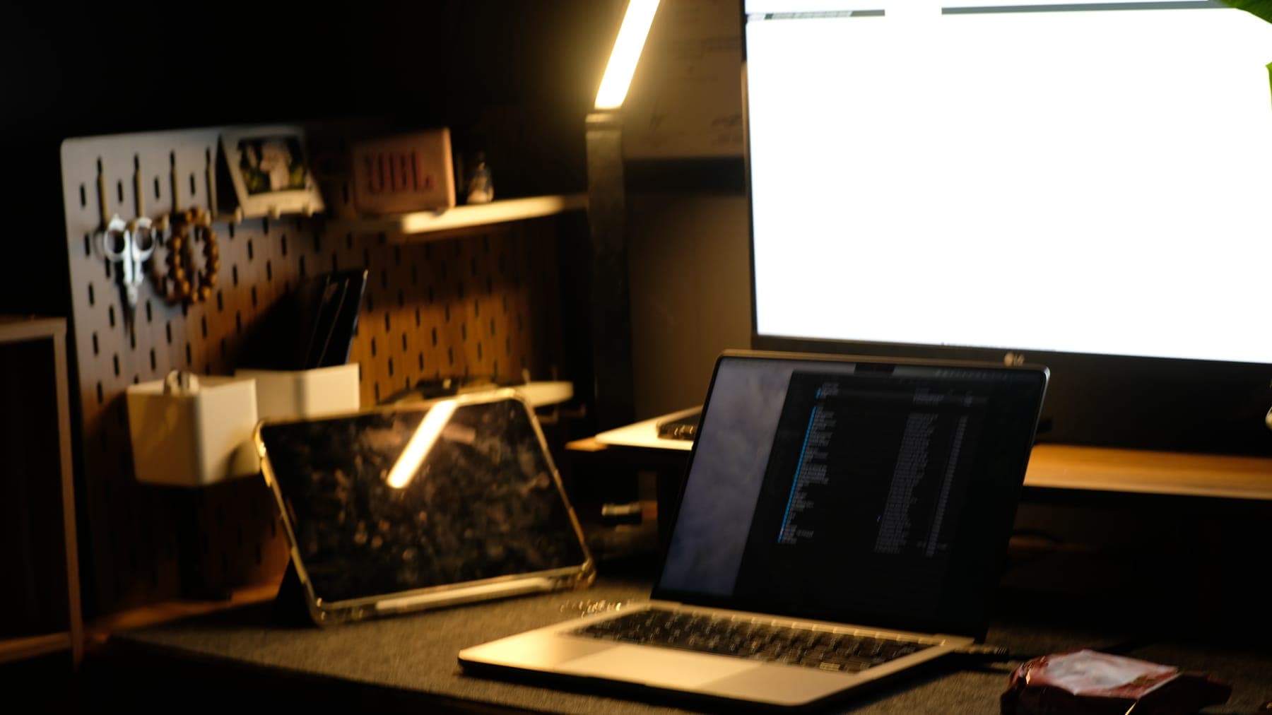 A dark room lit only by the monitor and a laptop